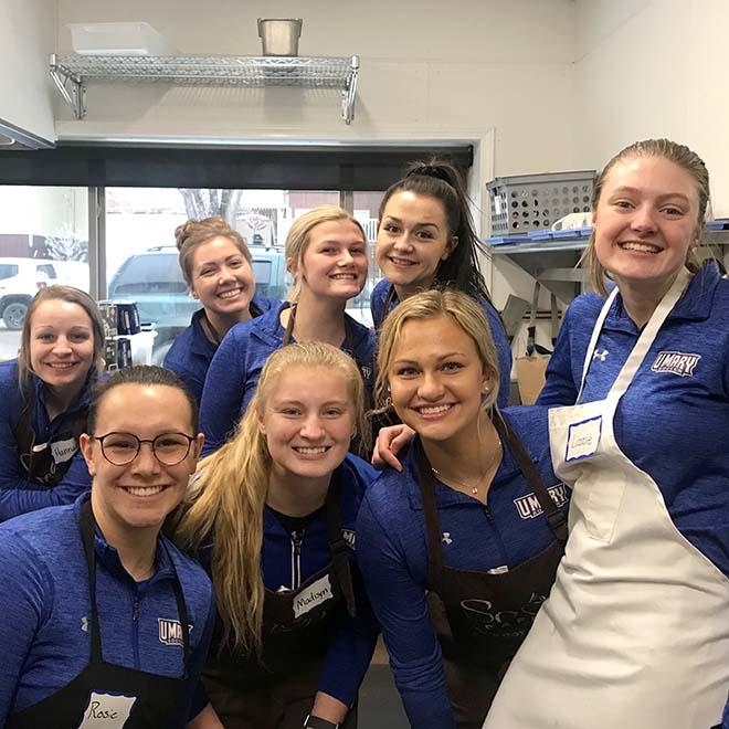 Eight female soccer players volunteering at soup kitchen
