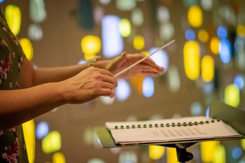 Conducting Hands with stain glass windows behind her