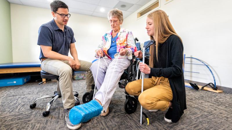 Students working with an elderly woman