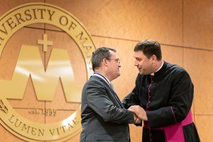 Patrick Reilly shaking hands with Monsignor James Shea 