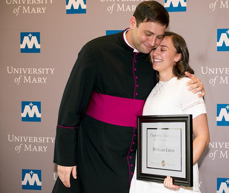 Morgan Ehlis getting a hug from Monsignor Shea