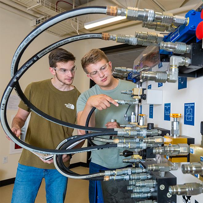 Engineering students working on Bobcat machinery.