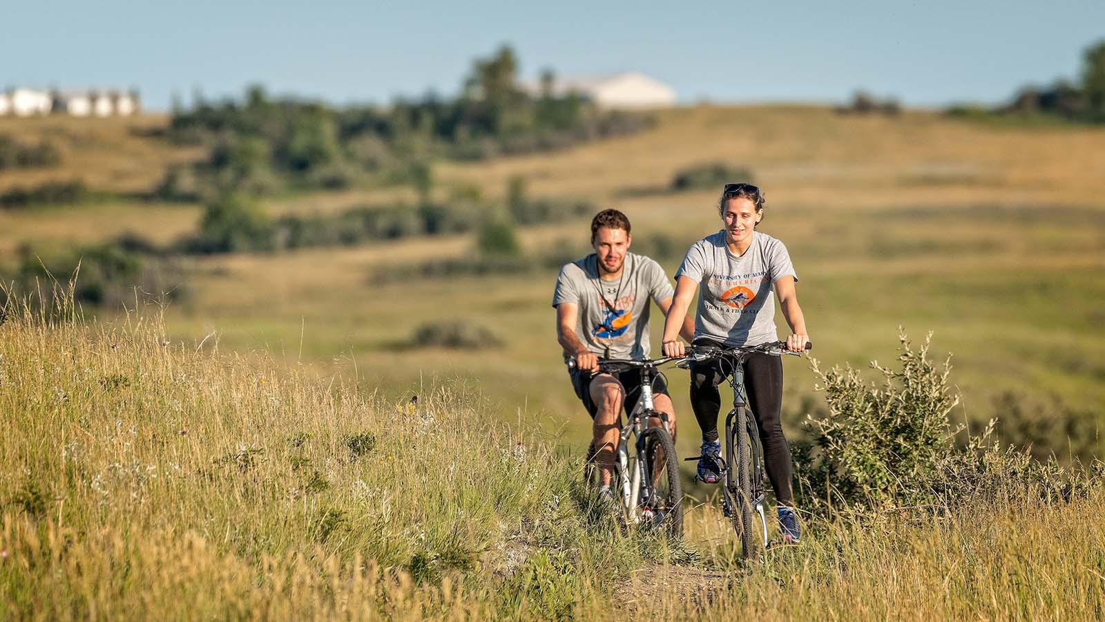 Couple riding mountain bikes on trail in countryside