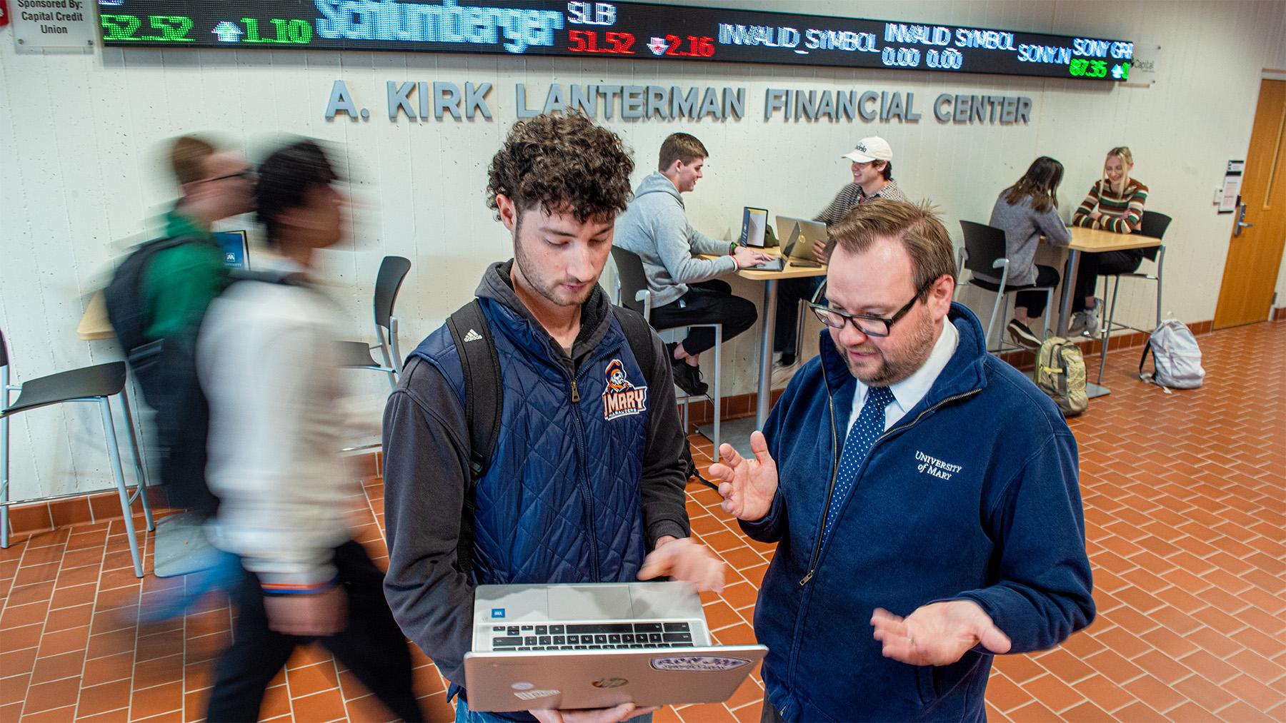 Student working with a profesor in the School of Business Hallway