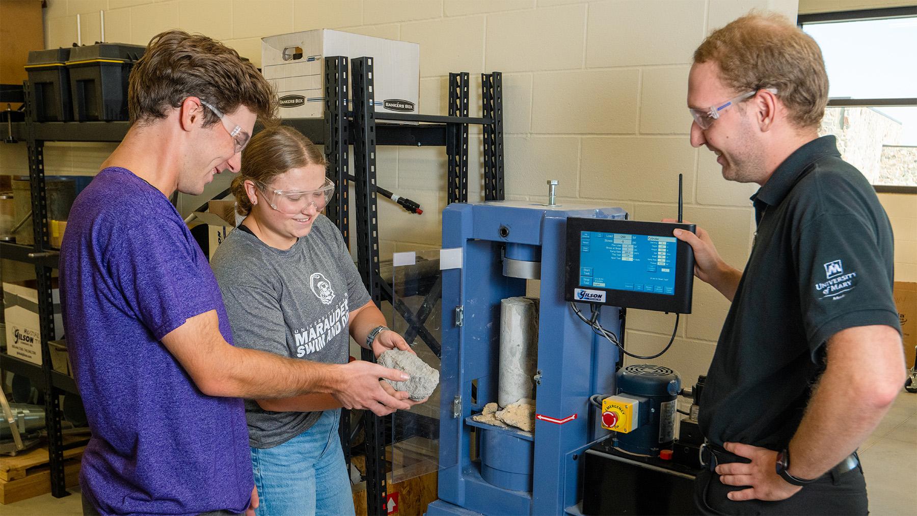 Three construction management students testing concrete.